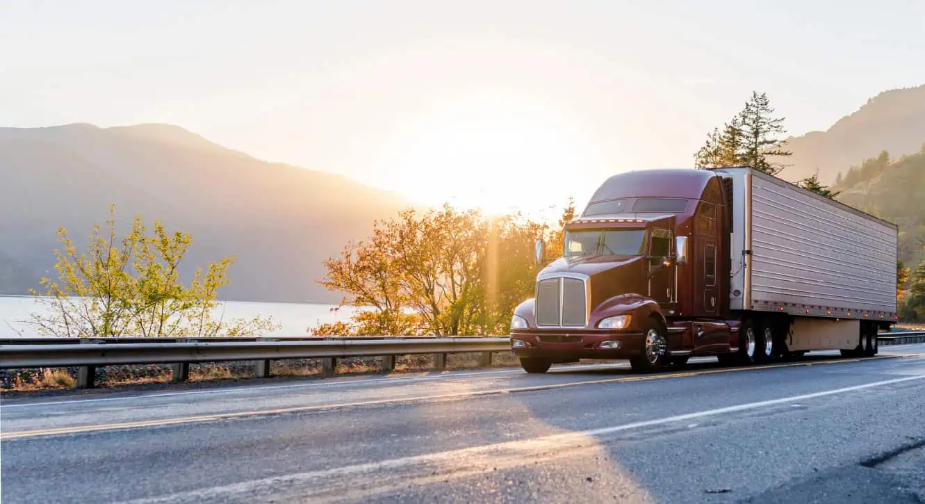 red truck driving down a road at sunrise
