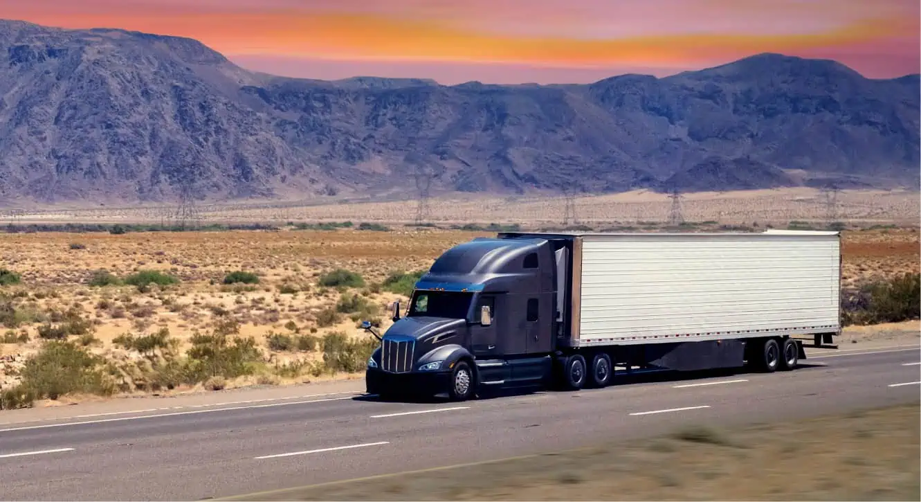 blue semi truck on highway during sunset