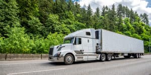 freight truck on highway next to wooded area