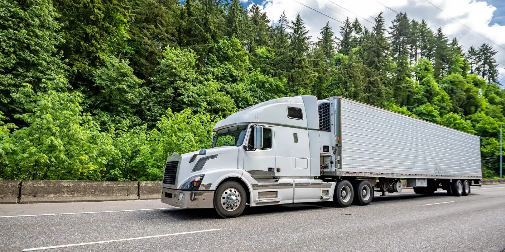 freight truck on highway next to wooded area