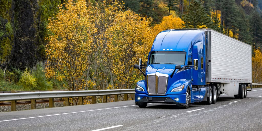 blue freight truck driving on highway