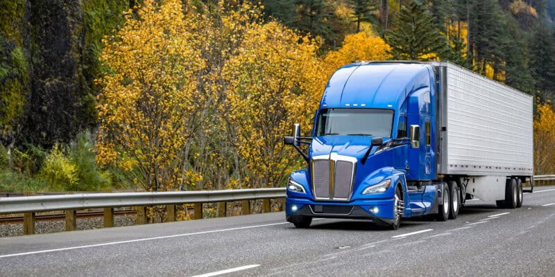 blue freight truck driving on highway